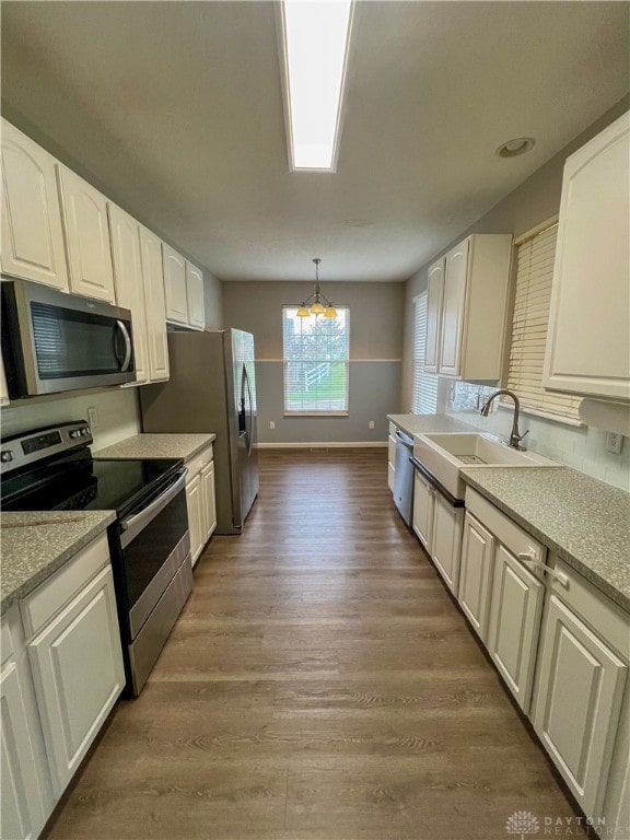 kitchen featuring appliances with stainless steel finishes, hardwood / wood-style flooring, decorative light fixtures, and sink