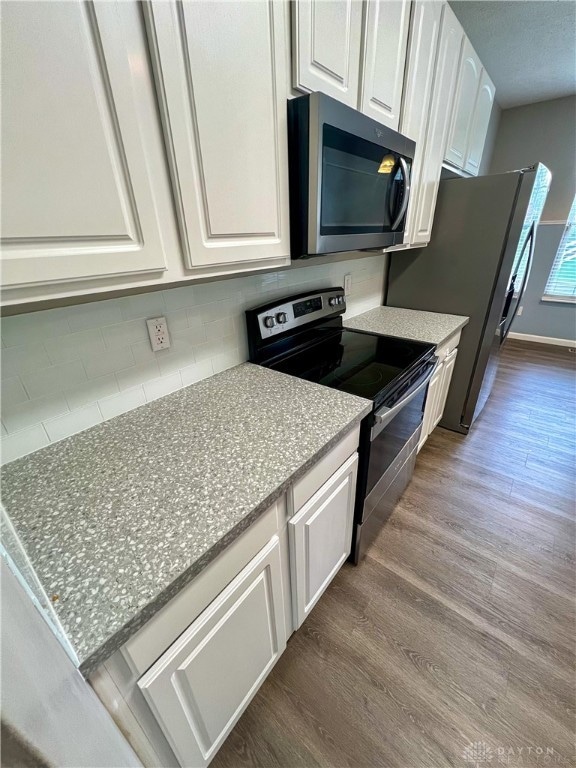 kitchen featuring white cabinetry, stainless steel appliances, light stone countertops, and dark hardwood / wood-style floors