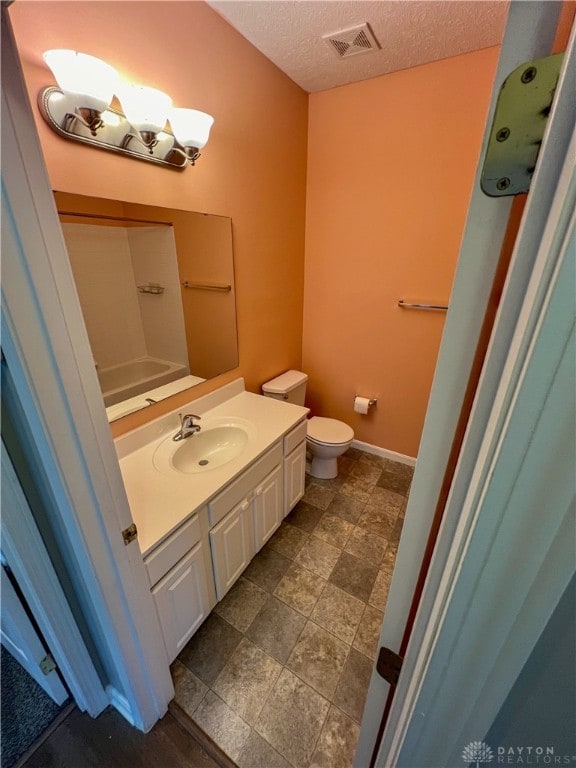 bathroom featuring vanity, toilet, and a textured ceiling