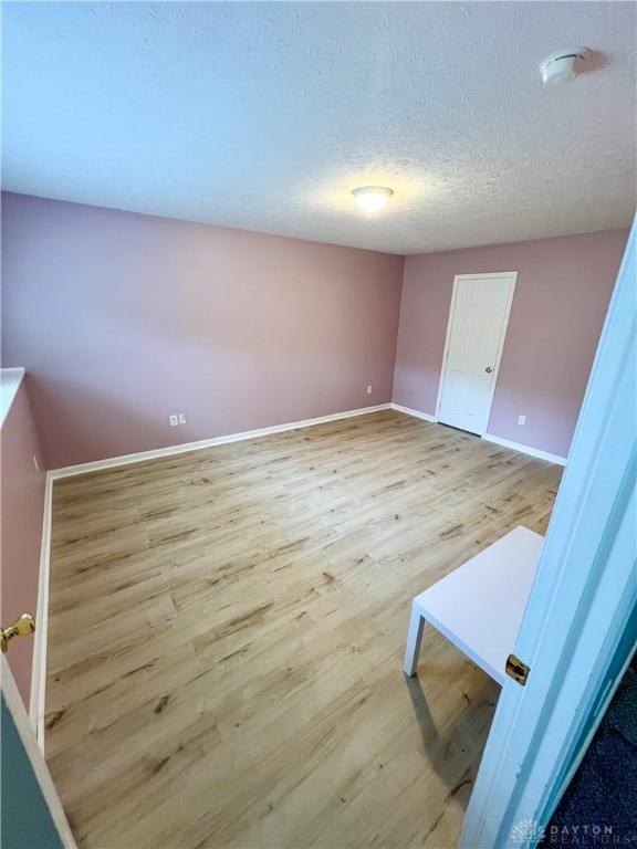 empty room with light hardwood / wood-style flooring and a textured ceiling