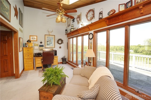 living room with wood ceiling, ceiling fan, a towering ceiling, and light carpet