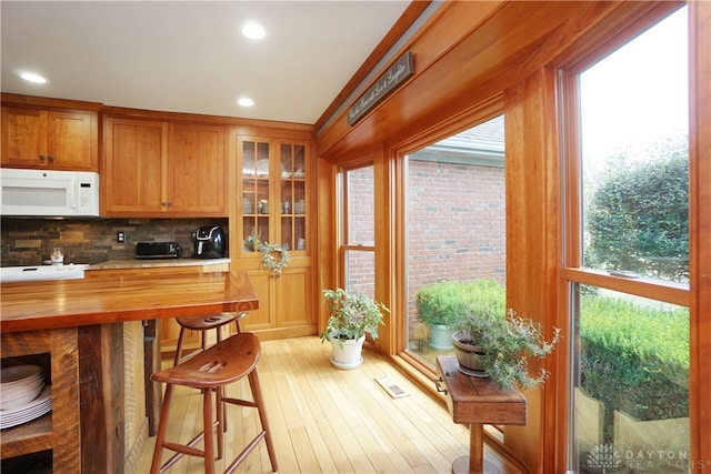 kitchen with light wood-type flooring, decorative backsplash, and a healthy amount of sunlight