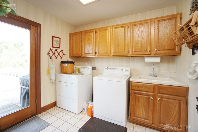 washroom with light tile patterned floors, washing machine and clothes dryer, cabinets, and sink