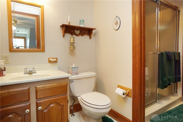 bathroom featuring ceiling fan, toilet, a shower with door, and vanity