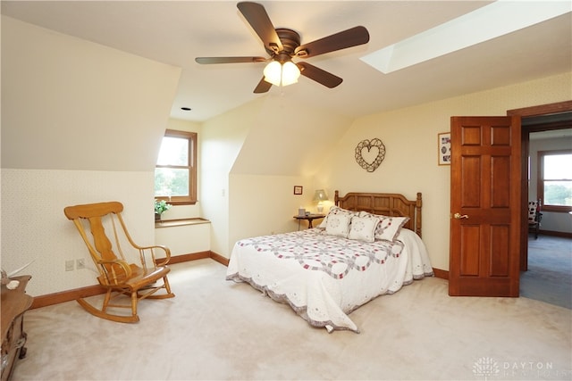 bedroom featuring multiple windows, ceiling fan, light colored carpet, and lofted ceiling with skylight