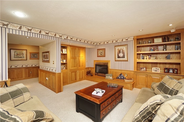 carpeted living room featuring a textured ceiling, wood walls, and built in shelves