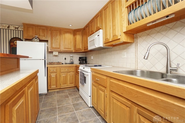 kitchen with dark tile patterned floors, sink, white appliances, and decorative backsplash