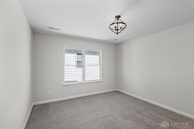 unfurnished room featuring a chandelier and carpet floors