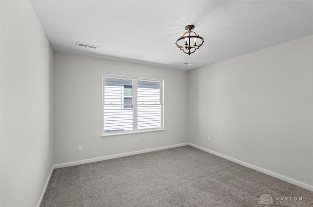 carpeted empty room with an inviting chandelier, visible vents, and baseboards