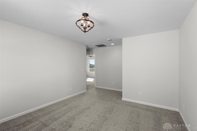 unfurnished room with carpet and an inviting chandelier