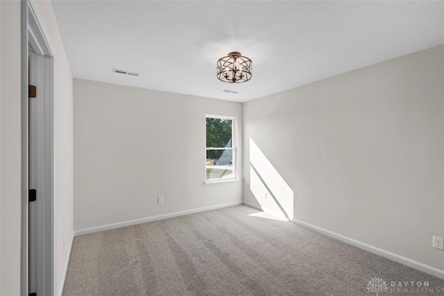 carpeted empty room with a chandelier