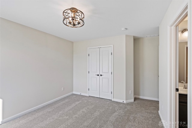 unfurnished bedroom with light carpet, an inviting chandelier, and a closet