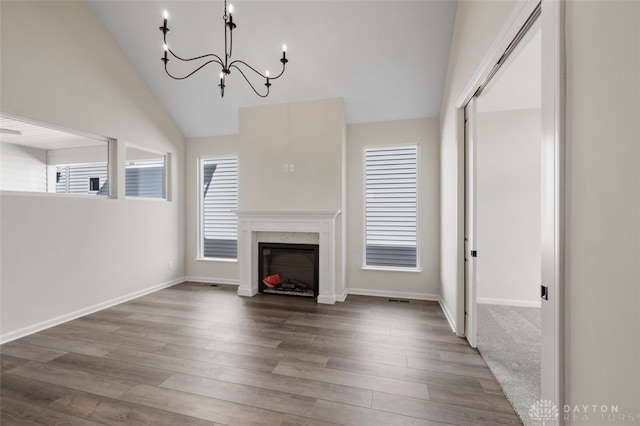 unfurnished living room with a premium fireplace, hardwood / wood-style flooring, an inviting chandelier, and lofted ceiling