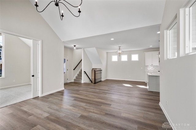 unfurnished living room with vaulted ceiling, a notable chandelier, and hardwood / wood-style floors