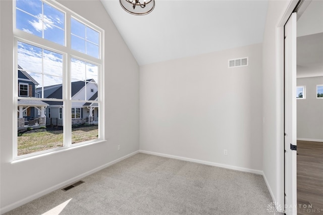 carpeted empty room featuring vaulted ceiling and a wealth of natural light