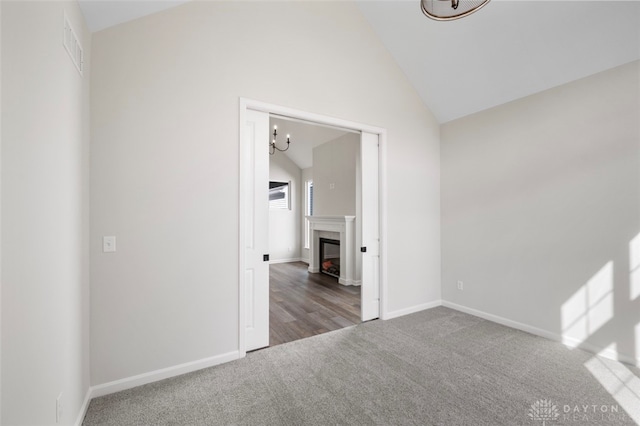 carpeted spare room featuring vaulted ceiling