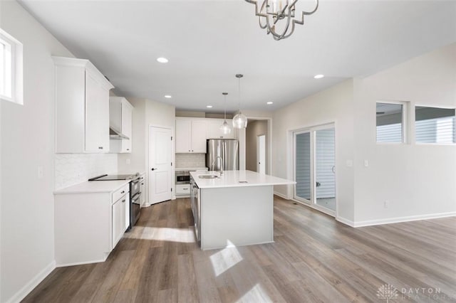 kitchen with light countertops, wood finished floors, backsplash, and freestanding refrigerator