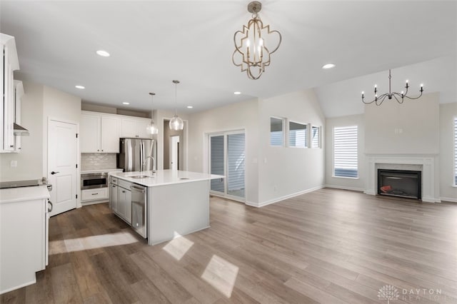 kitchen with dark hardwood / wood-style floors, a center island with sink, hanging light fixtures, stainless steel appliances, and a chandelier