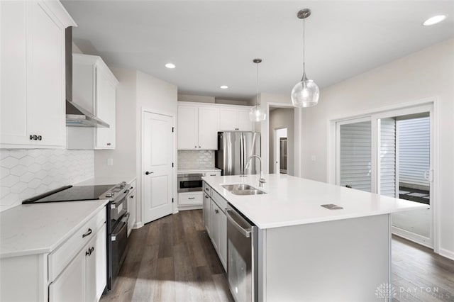 kitchen featuring decorative light fixtures, dark hardwood / wood-style flooring, appliances with stainless steel finishes, a kitchen island with sink, and sink