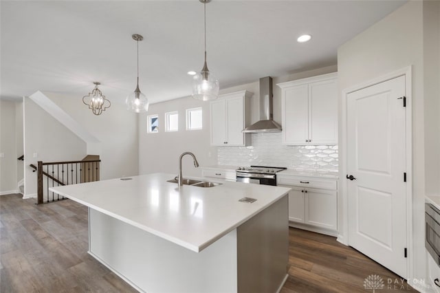 kitchen featuring a kitchen island with sink, wall chimney exhaust hood, white cabinetry, and stainless steel range with electric cooktop