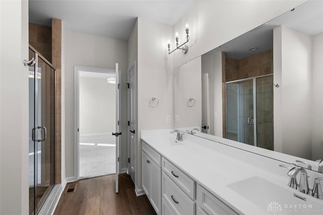 bathroom featuring hardwood / wood-style flooring, a shower with door, and vanity