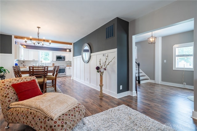 living room with a chandelier and dark wood-type flooring