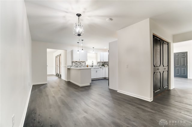 kitchen with a notable chandelier, dark hardwood / wood-style flooring, sink, hanging light fixtures, and white cabinets