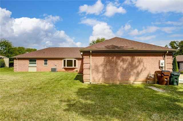 back of property with central air condition unit and a yard