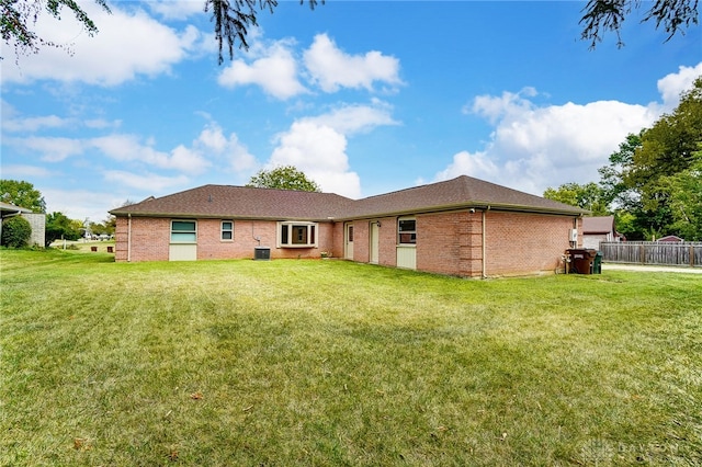 rear view of house featuring a lawn and central AC unit