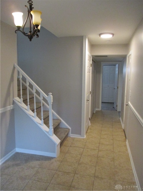 corridor featuring a notable chandelier and light tile patterned floors