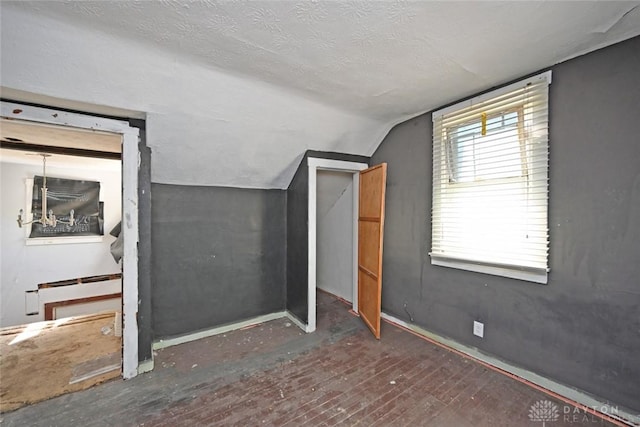 additional living space featuring a textured ceiling, dark hardwood / wood-style floors, and lofted ceiling