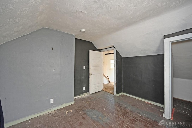 additional living space with dark hardwood / wood-style floors, lofted ceiling, and a textured ceiling