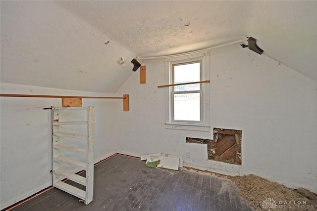 additional living space featuring lofted ceiling, a textured ceiling, and dark wood-type flooring