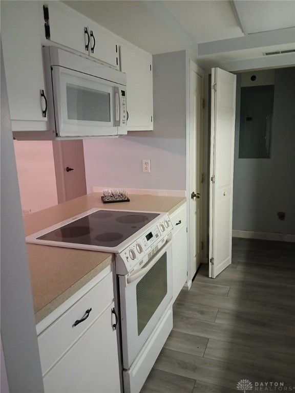 kitchen with electric panel, white cabinetry, light hardwood / wood-style floors, and white appliances