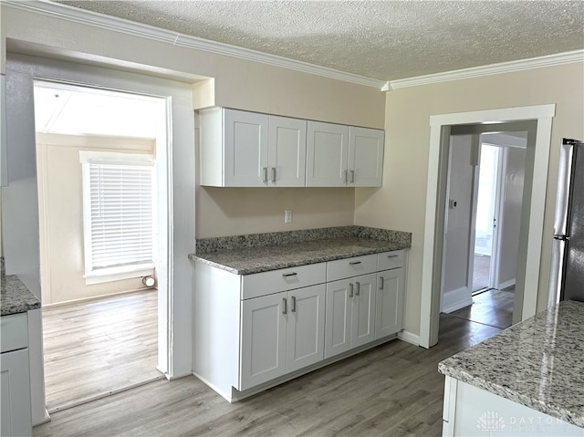 kitchen featuring white cabinets, light hardwood / wood-style floors, a textured ceiling, and stainless steel fridge