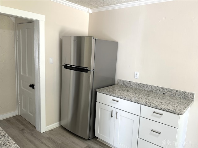 kitchen featuring light wood-type flooring, stainless steel fridge, crown molding, and white cabinetry