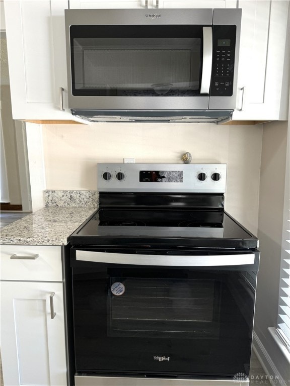 kitchen featuring appliances with stainless steel finishes, light stone counters, and white cabinets