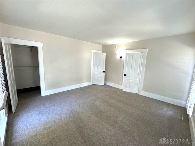 unfurnished bedroom with a closet and dark colored carpet