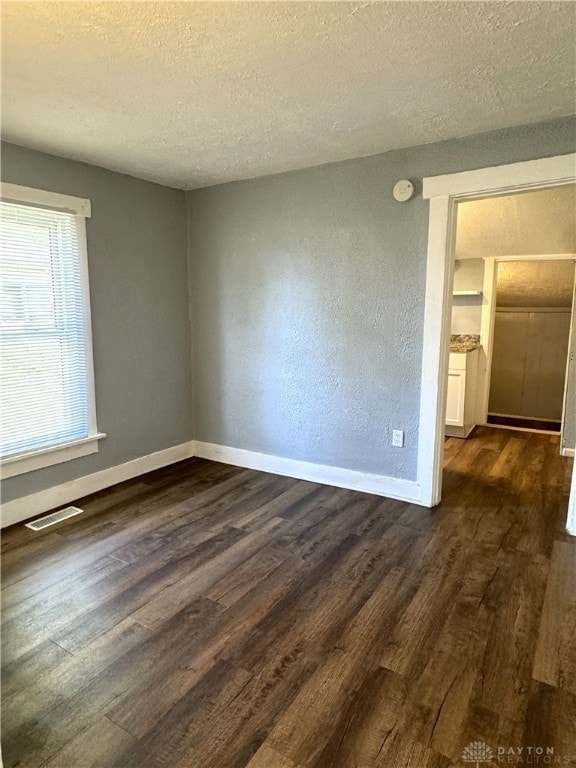 unfurnished room featuring a textured ceiling and dark wood-type flooring