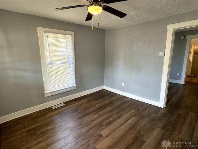 empty room featuring a textured ceiling, dark hardwood / wood-style floors, and ceiling fan