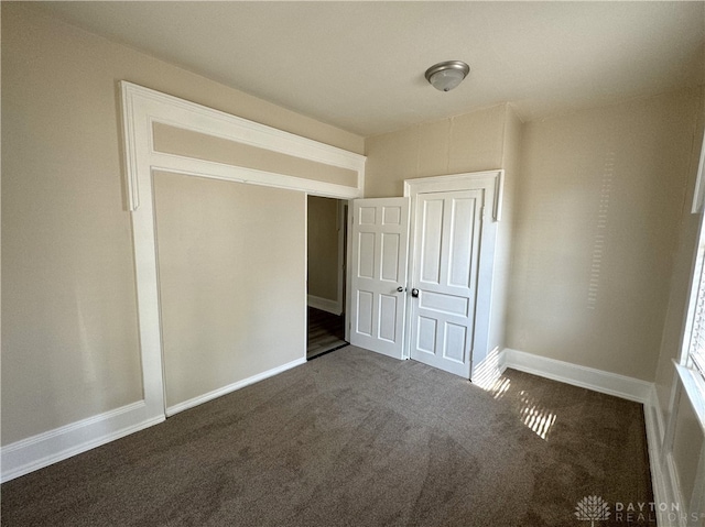 unfurnished bedroom featuring dark colored carpet and a closet