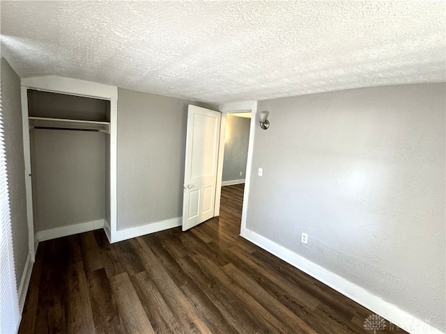 unfurnished bedroom featuring a textured ceiling, a closet, and dark hardwood / wood-style flooring