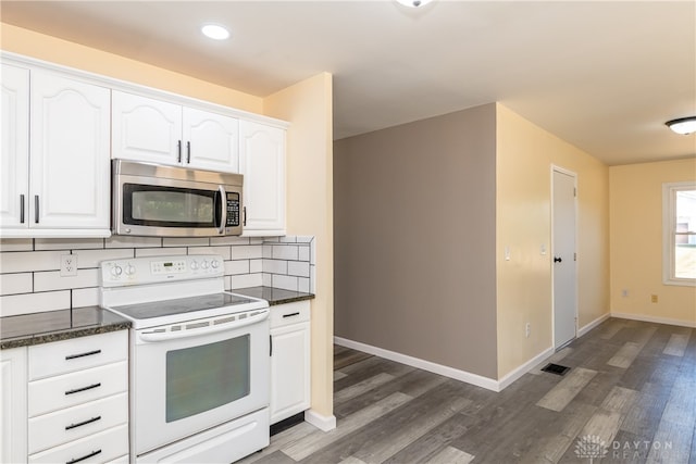 kitchen with backsplash, dark stone counters, white electric range, dark hardwood / wood-style flooring, and white cabinetry