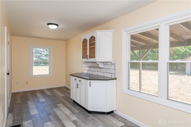 kitchen with light hardwood / wood-style floors, dark stone countertops, white cabinetry, and backsplash