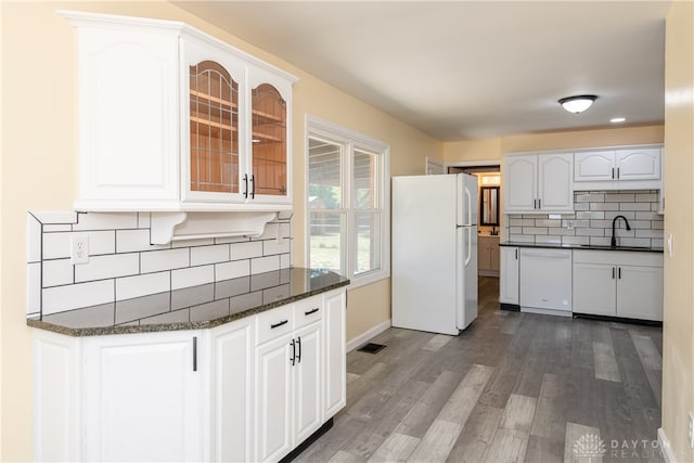 kitchen featuring dark wood-type flooring, dark stone counters, white appliances, decorative backsplash, and white cabinets