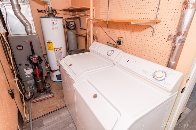 laundry room featuring light wood-type flooring, a workshop area, gas water heater, and washing machine and clothes dryer