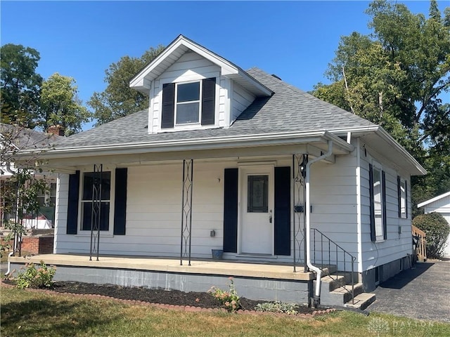 bungalow with a porch and roof with shingles