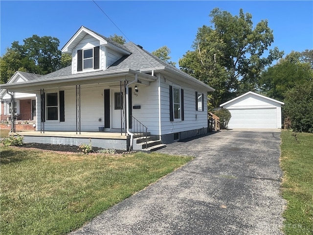 view of front facade with a garage, covered porch, an outbuilding, and a front yard