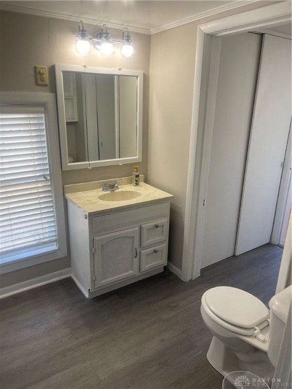 bathroom with wood-type flooring, toilet, ornamental molding, and vanity