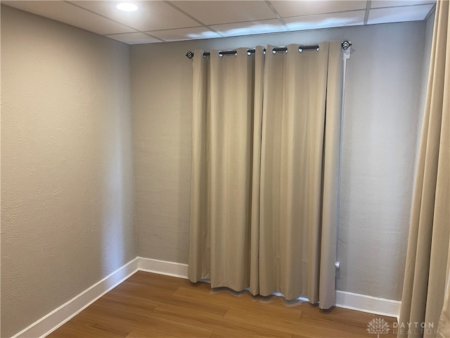 unfurnished room featuring hardwood / wood-style floors and a paneled ceiling